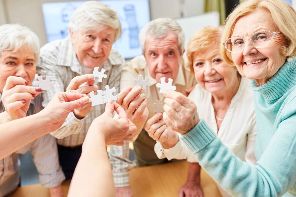 Demenzkranke Senioren spielen ein Puzzlespiel als Gedächtnistraining in einem Pflegeheim