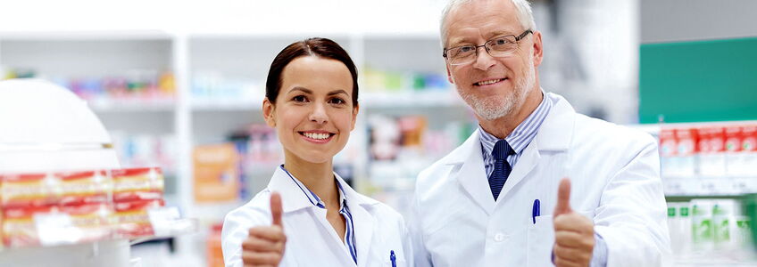 Medizin, Gesundheitswesen und Technologiekonzept – fröhliche, lächelnde Apotheker in einer Apotheke, die den Daumen hochhalten